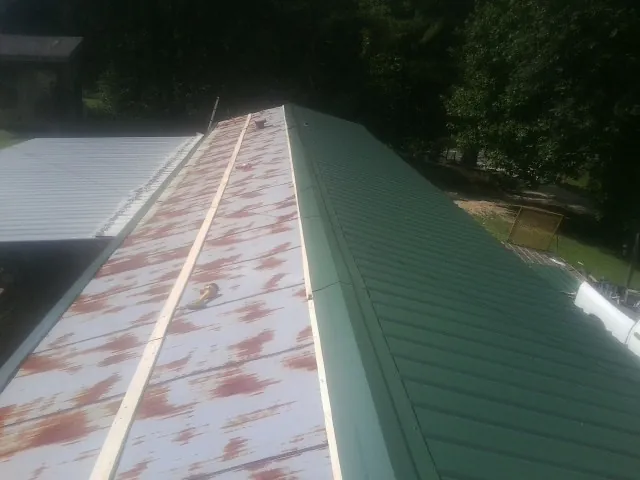 Old rusted panels beside newly installed green metal roofing — Wind Damage Roof Repair by Roofing Brothers in Egg Harbor City