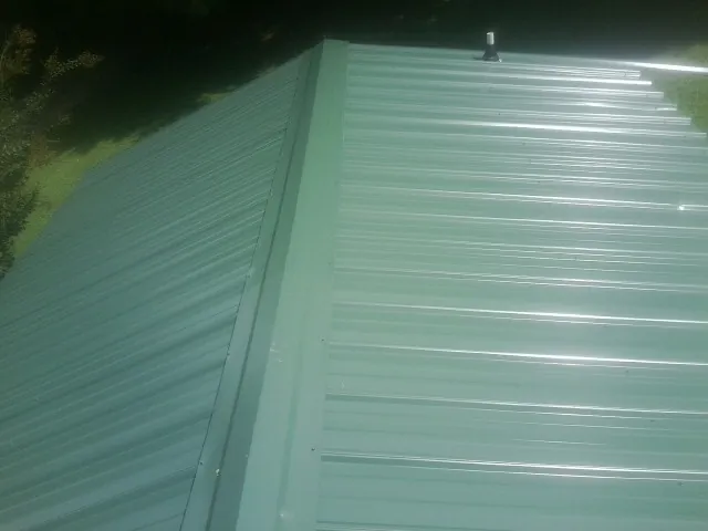 New green metal panels meeting at the ridge of a roof — Flat Roof Repair work by our crew in Egg Harbor City