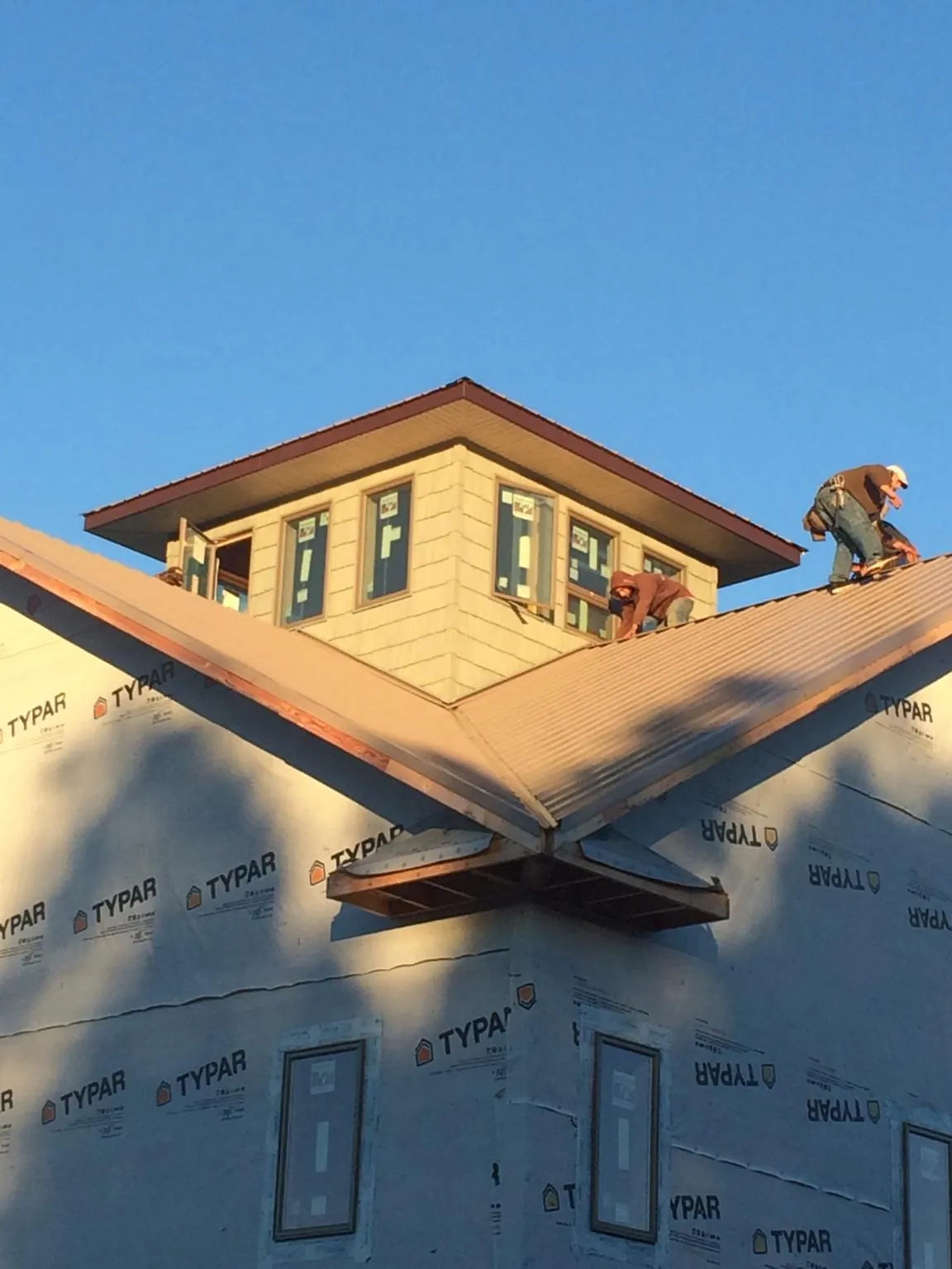 Roofers working around a rooftop cupola on a new metal roof at sunset — Roof Waterproofing in Egg Harbor City by Roofing Brothers